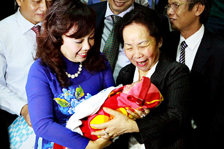 Phó Chủ tịch nước Nguyễn Thị Doan, Bộ trưởng Bộ Y tế Nguyễn Thị Kim Tiến vui mừng đón và bế em bé Nguyễn Thị Thùy Dung, công dân thứ 90 triệu của Việt Nam. 